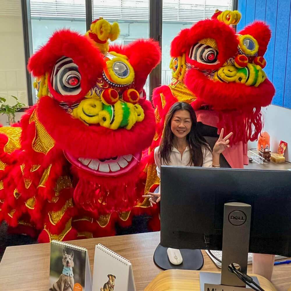 Woman at desk in OIA Singapore Tai Seng Exchange surrounded by two large, artistic dragon costumes.