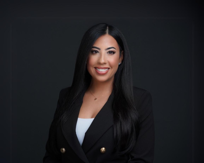 2024 Women in Supply Chain Award recipient, Alisha Gonzalez, pictured in dark business attire in front of a dark background.